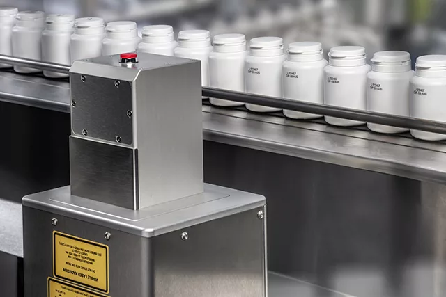 UV-laser for industriell merking: Linx UVG5 merker fra siden på plastbokser.